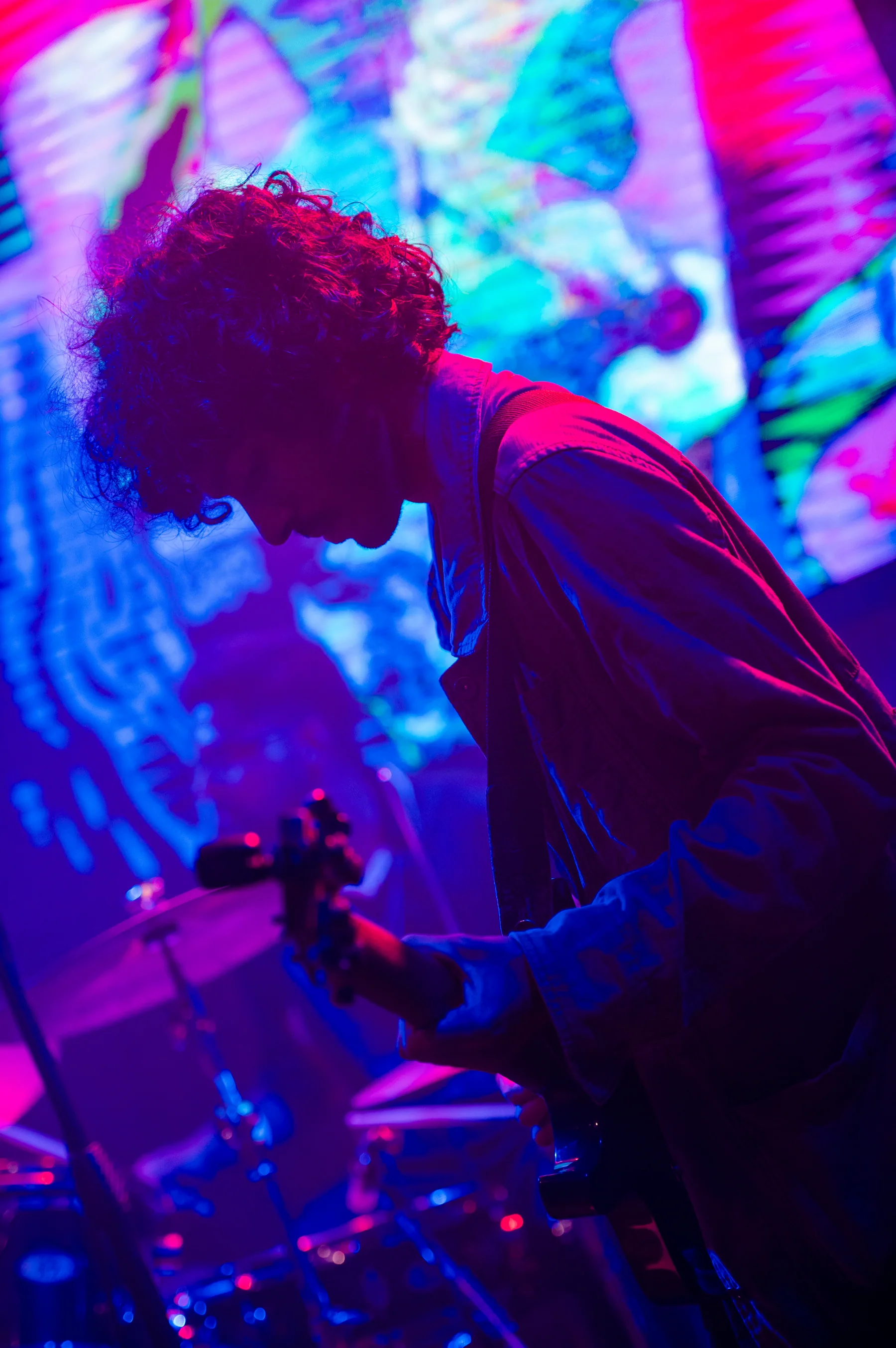 Guitarist framed by bright live visuals.