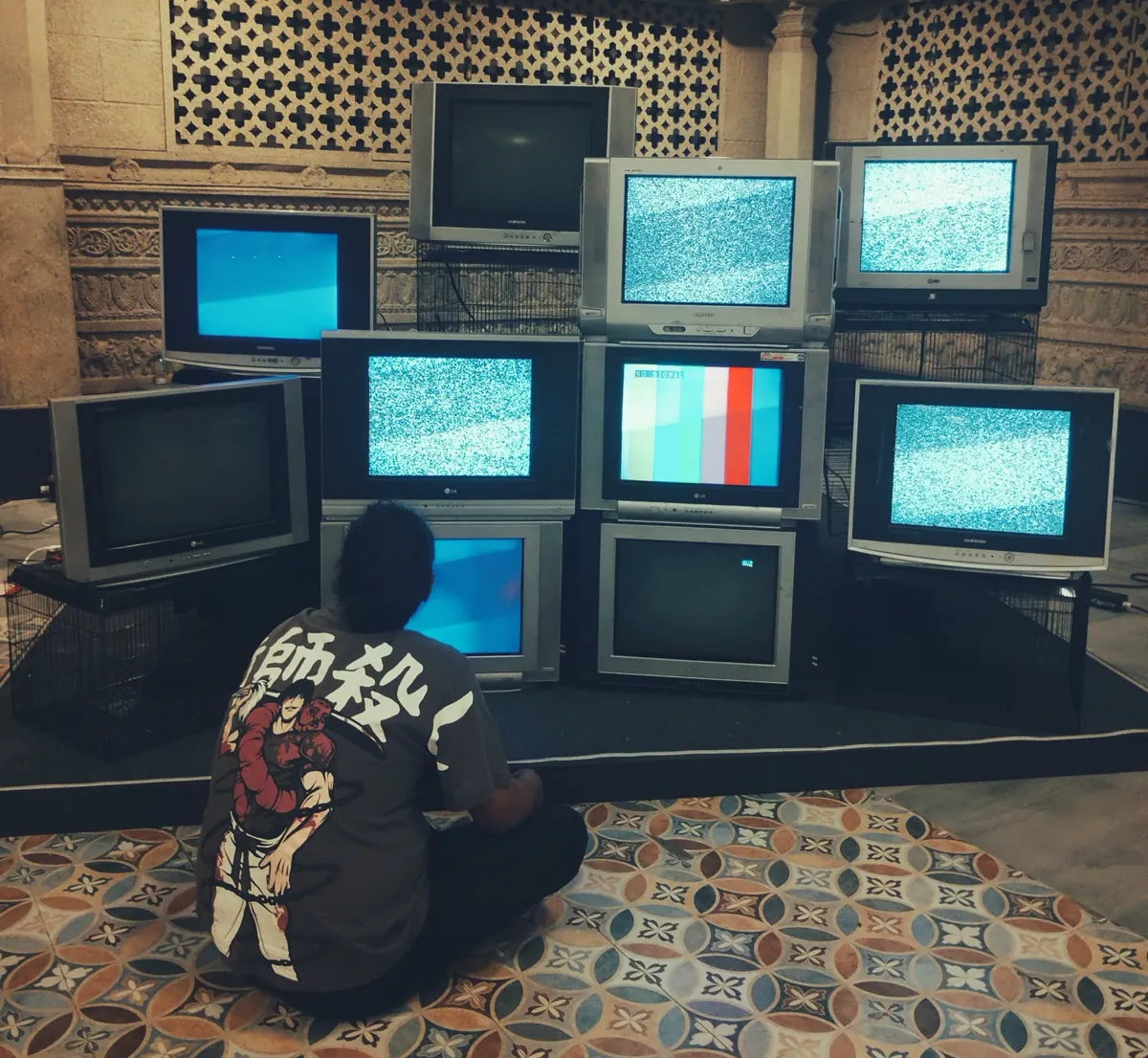 Nine stacked CRT televisions showing static and colour bars during setup.
