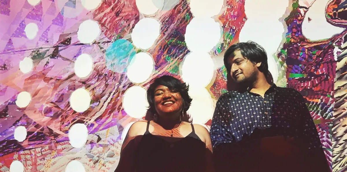 Rhea Fabian and Srinivas Vijayakumar standing before projected live visuals.