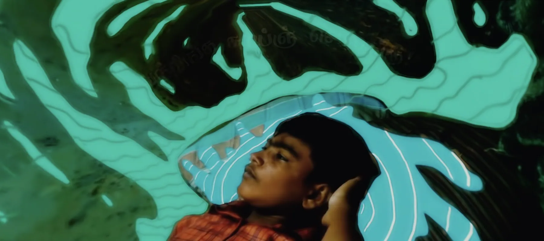 A boy asleep among teal painted leaves.